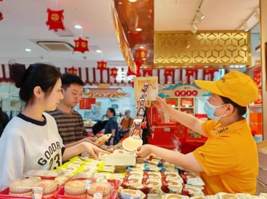北京稻香村一家門店內(nèi)，售貨員向顧客展示新上市的月餅禮盒。（受訪者供圖）