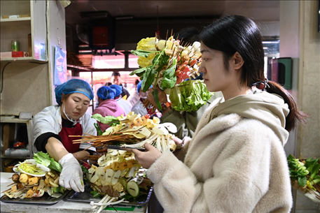 游客挑選好麻辣燙菜品后排隊等待加工。新華社記者 范培珅 攝