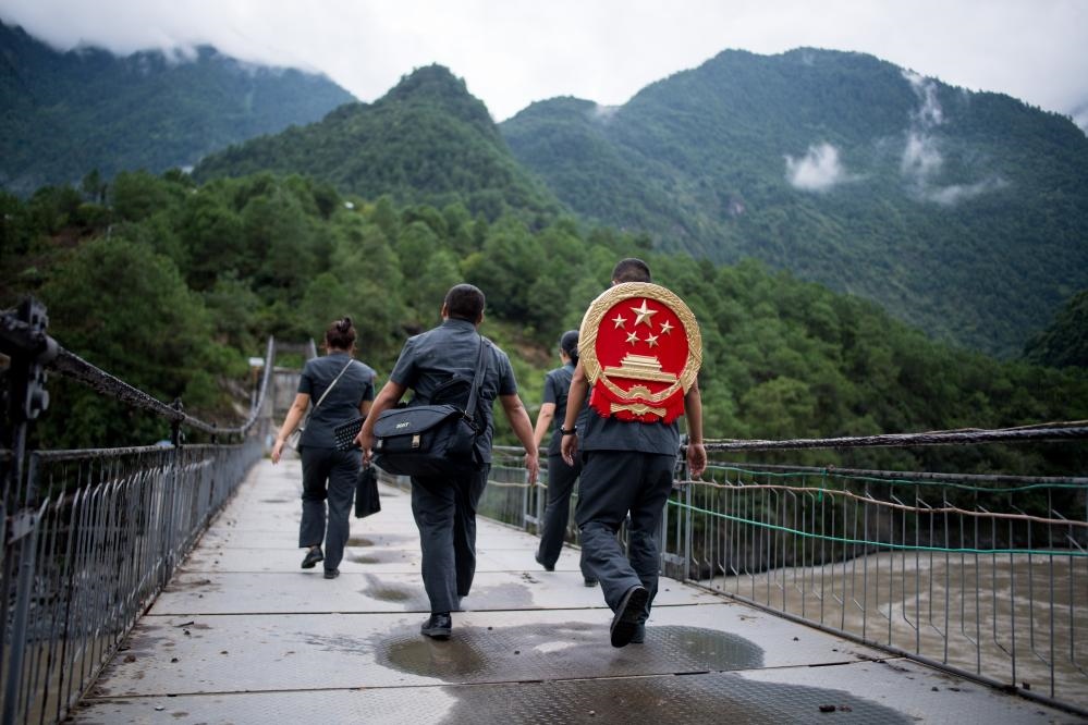 云南省怒江傈僳族自治州貢山縣人民法院法官鄧興背著國(guó)徽與同事們跨過(guò)怒江（2019年8月30日攝）。怒江高山峽谷眾多，交通不便，為方便群眾、更好地開(kāi)展法律服務(wù)，背著國(guó)徽攀高山、過(guò)索橋、躲落石、鉆老林……成為鄧興法官的工作常態(tài)。新華社記者 江文耀 攝