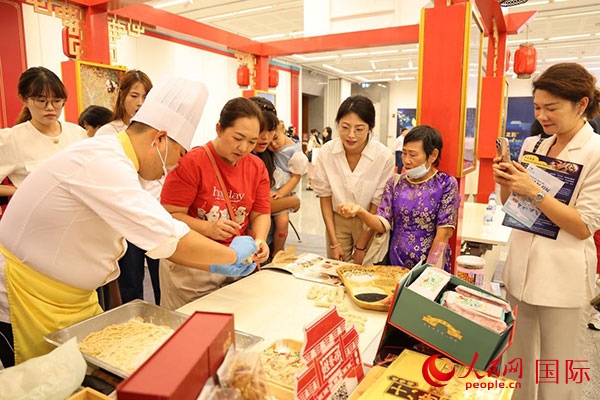 演出前，在天津桂發(fā)祥十八街麻花制作技藝非遺體驗展臺前，泰國民眾體驗天津麻花制作。人民網記者 楊一攝