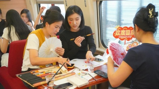 10月1日，旅客們在G1634次列車上給油紙傘作畫。新華社記者周義 攝