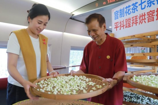10月1日，福州市茉莉花茶窨制工藝代表性傳承人張子建與旅客在G1634次列車上制作茉莉花茶。新華社記者周義 攝