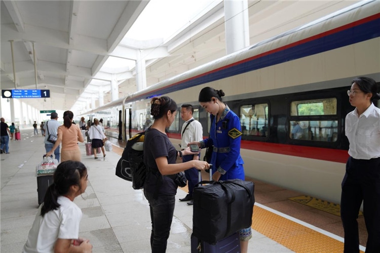 中老鐵路工作人員在站臺指引旅客進(jìn)站乘車。老中鐵路有限公司供圖