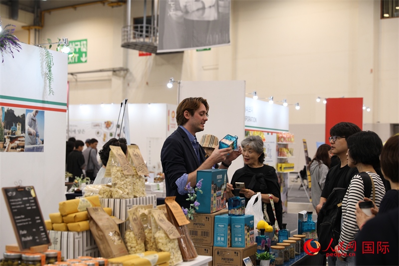 當(dāng)?shù)貢r間10月5日，在第21屆釜山國際美食博覽會上，意大利展商向參觀者們介紹的意大利食品。人民網(wǎng)記者 莽九晨攝