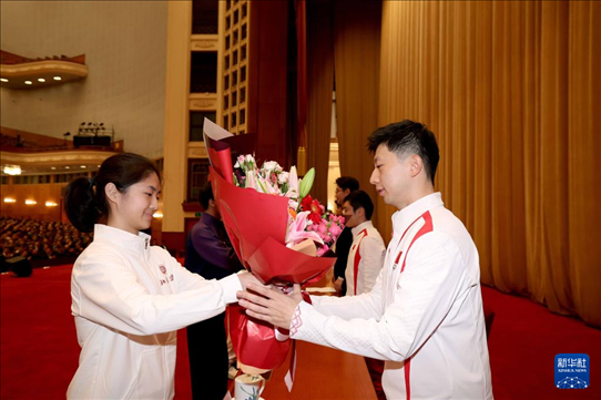 11月15日，一名學(xué)生代表在報告會上向乒乓球運動員馬龍（右）獻花。新華社記者 李明 攝