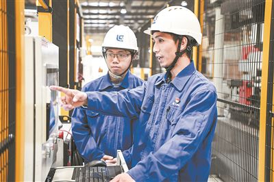 在廣西柳工機(jī)械股份有限公司生產(chǎn)車(chē)間內(nèi)，一名高級(jí)技師（右）給徒弟講解數(shù)控設(shè)備操作細(xì)節(jié)。新華社記者 曹祎銘攝