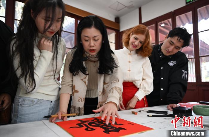 1月20日，西泠印社社員李硯（左二）為外籍留學(xué)生講述蛇年福字貼創(chuàng)作靈感。當(dāng)日，來自巴西、馬來西亞、加納、哈薩克斯坦的外籍留學(xué)生在浙江杭州西泠印社體驗福貼、春聯(lián)和篆刻，感受古老的中國傳統(tǒng)文化。中新社記者 王剛 攝