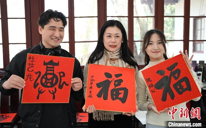 1月20日，外籍留學(xué)生和西泠印社社員李硯(中)展示各自創(chuàng)作的福貼。當(dāng)日，來自巴西、馬來西亞、加納、哈薩克斯坦的外籍留學(xué)生在浙江杭州西泠印社體驗福貼、春聯(lián)和篆刻，感受古老的中國傳統(tǒng)文化。中新社記者 王剛 攝