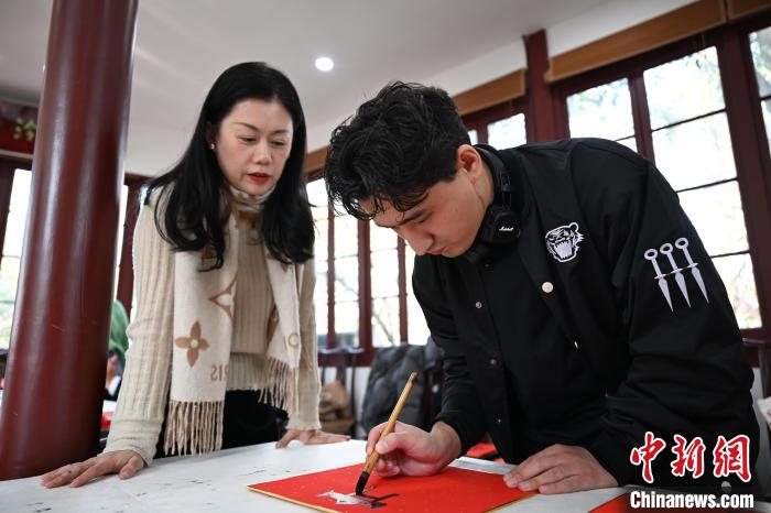 1月20日，外籍留學(xué)生在西泠印社社員李硯指導(dǎo)下寫福。當(dāng)日，來自巴西、馬來西亞、加納、哈薩克斯坦的外籍留學(xué)生在浙江杭州西泠印社體驗福貼、春聯(lián)和篆刻，感受古老的中國傳統(tǒng)文化。中新社記者 王剛 攝