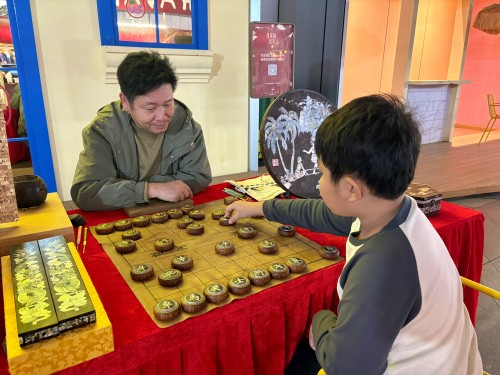 柯秋楓與市民下椰雕象棋。人民網(wǎng) 陳葉欣攝