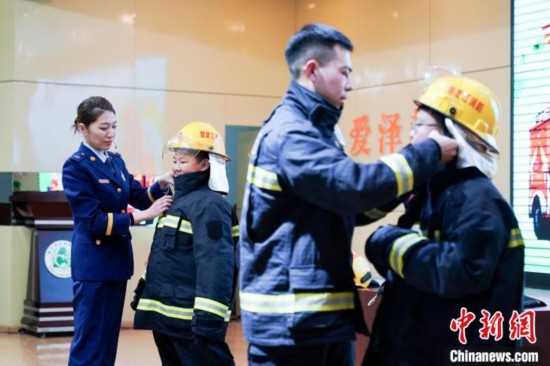 圖為學生們現場穿戴消防頭盔和戰(zhàn)斗服。中新社記者 趙宇航 攝