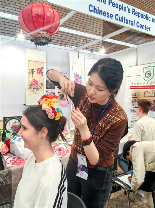 展覽正值羅馬尼亞迎春花節(jié)，國際中文教師志愿者潘婧穎向游客們介紹了國家非物質(zhì)文化遺產(chǎn)——福建泉州的簪花文化。布加勒斯特大學(xué)孔子學(xué)院供圖。