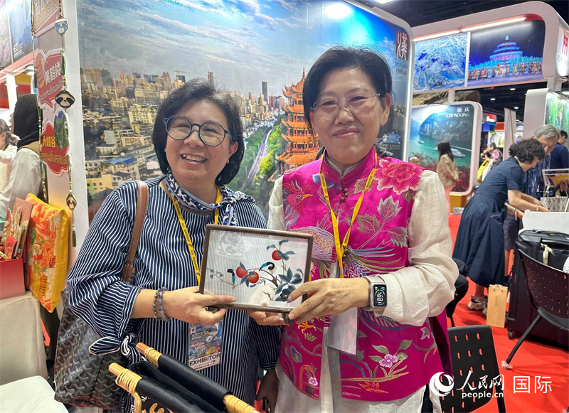 中國“大冶刺繡”傳承人劉小紅（右）參加泰國國際旅游展，向觀眾介紹中國非遺刺繡針法。人民網(wǎng)記者 簡承淵攝