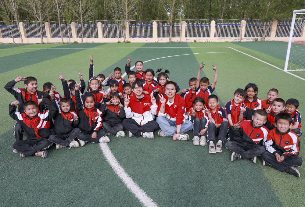 4月23日，在新疆克州阿圖什市哈拉峻鄉(xiāng)謝依特小學(xué)，支教教師王俊文（中左）、李軻凡（中右）和學(xué)生在一起。