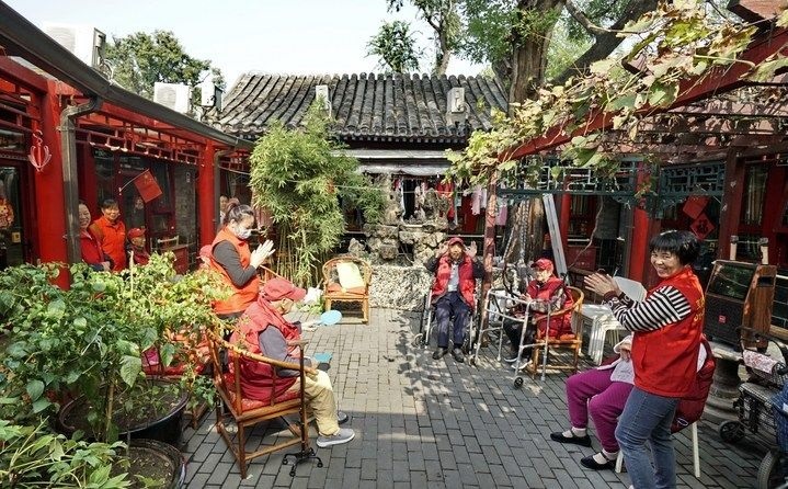 2024年10月12日，鐘樓灣胡同的老年人在社區(qū)內(nèi)的四合院養(yǎng)老驛站休閑。2017年起，北京市先后開(kāi)展了兩輪背街小巷環(huán)境整治提升行動(dòng)，完整保留了中軸線生活建筑群的歷史信息，并根據(jù)居民的生活和居住方式進(jìn)行適配化的更新和改造，極大地改善了生活環(huán)境。2023年鐘樓灣胡同被評(píng)為“北京最美街巷”。